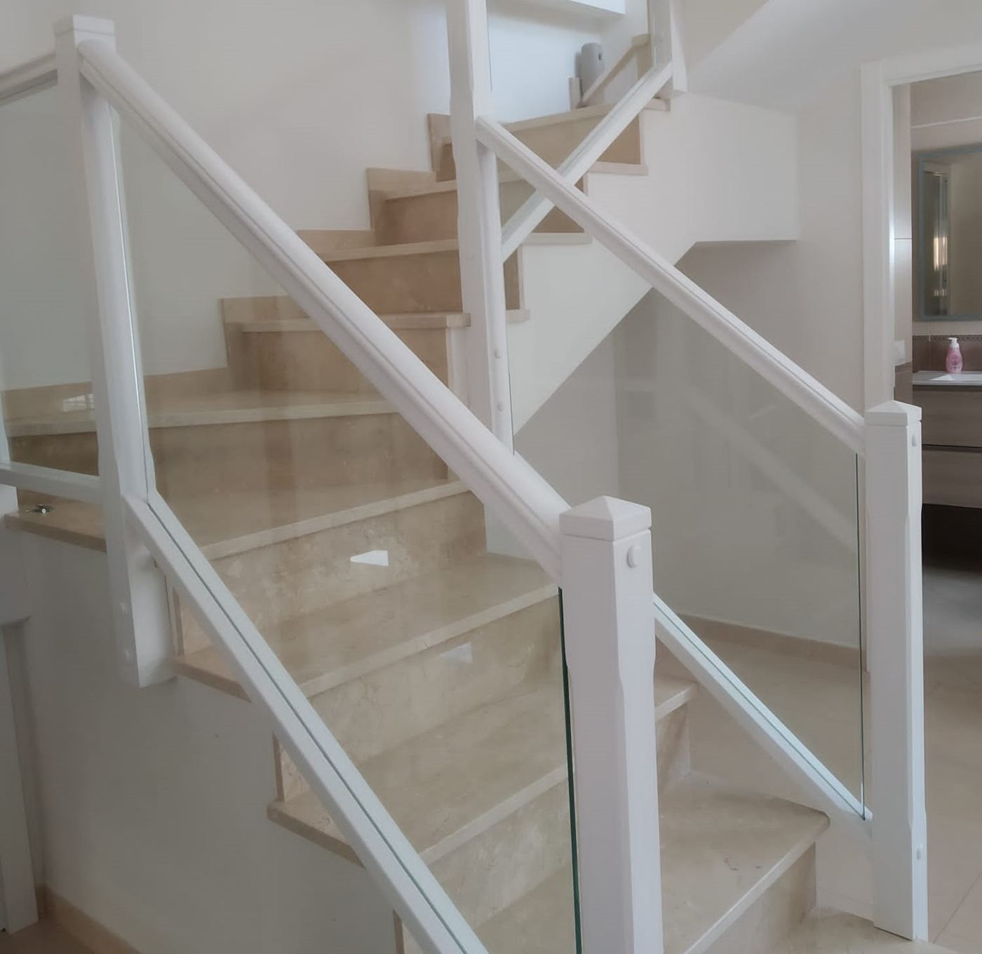 Barandilla de escalera con cristal templado y pasamanos blanco, montada por Cristalería Ruiz Arana